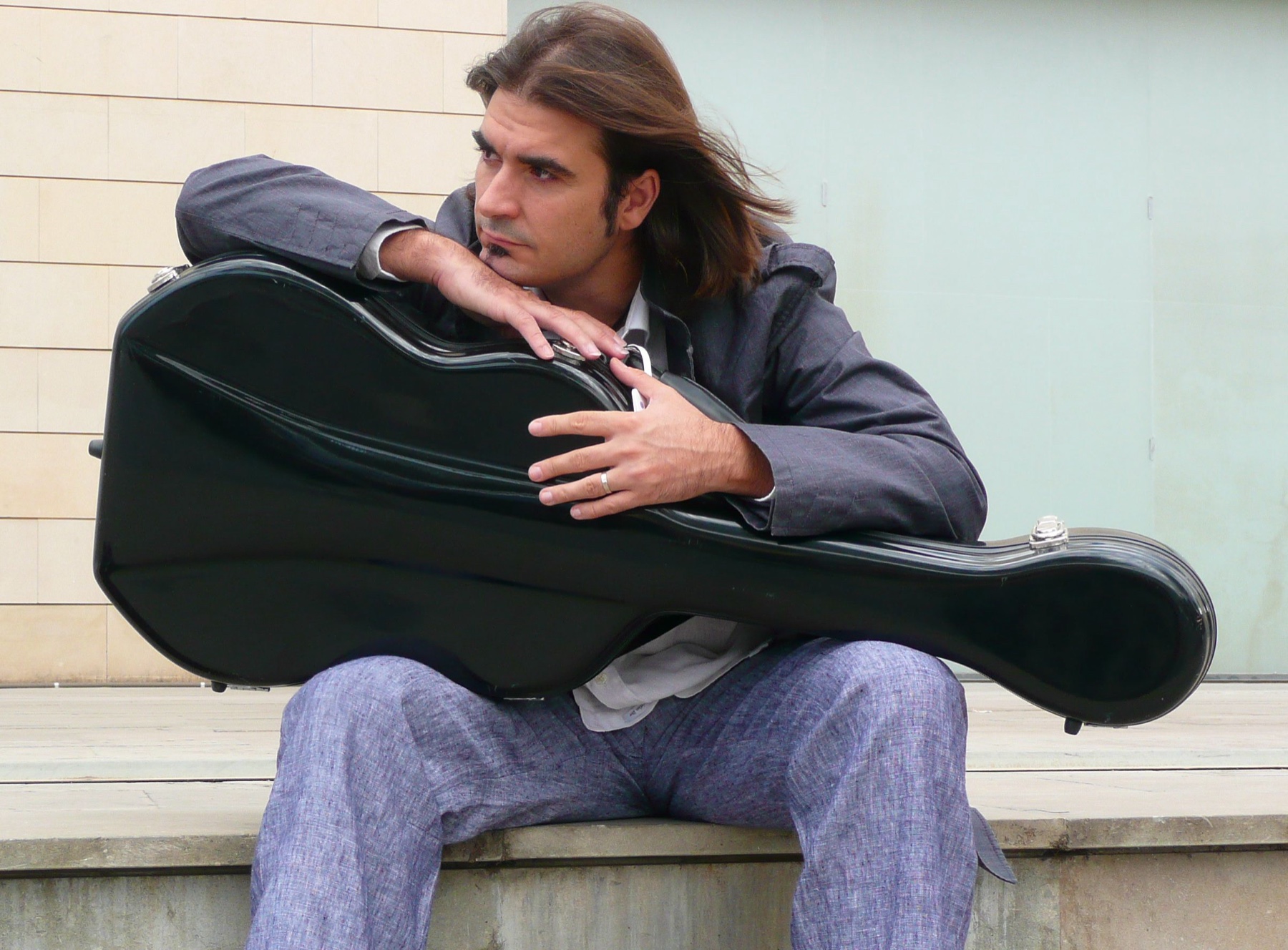 Rafael Serrallet seated with a guitar case