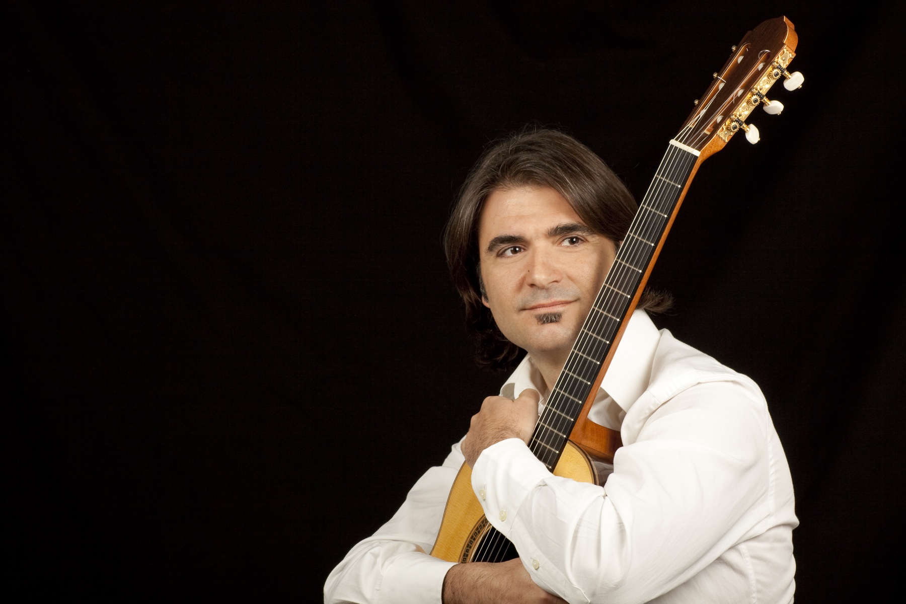 Rafael Serrallet holding a classical guitar in a formal portrait